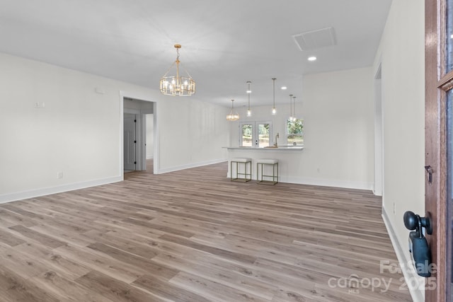 unfurnished living room featuring light hardwood / wood-style floors and a chandelier