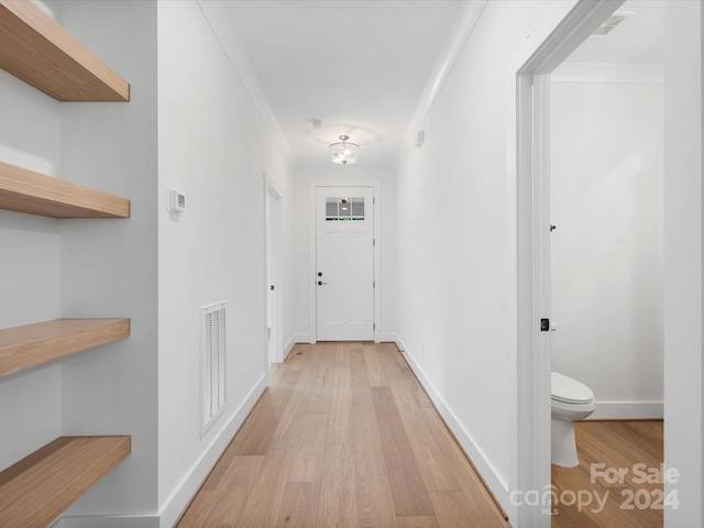 corridor featuring light wood-type flooring and crown molding