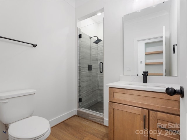 bathroom with hardwood / wood-style floors, walk in shower, vanity, and toilet