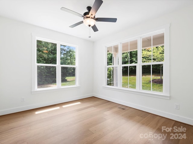 spare room featuring a wealth of natural light, ceiling fan, and light hardwood / wood-style flooring