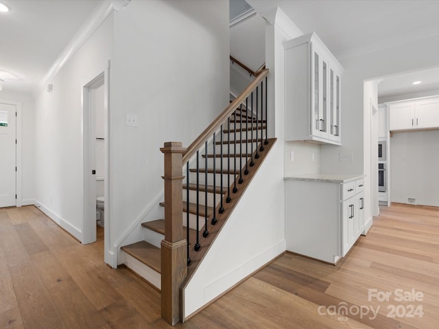 stairway featuring hardwood / wood-style flooring and crown molding