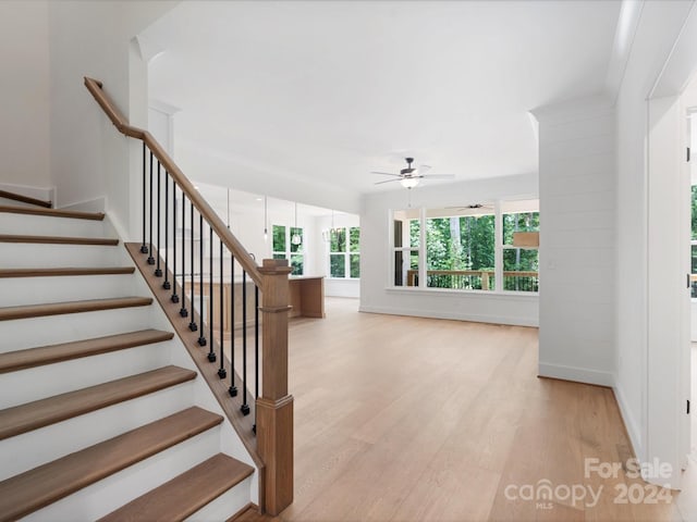 staircase with hardwood / wood-style flooring and ceiling fan