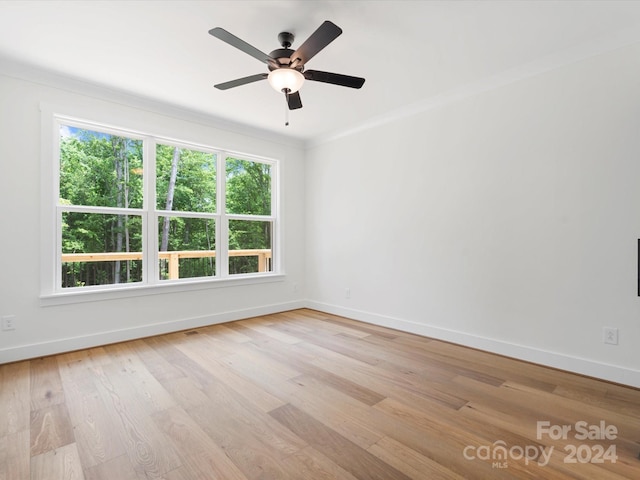 spare room featuring light wood-type flooring, a wealth of natural light, and crown molding