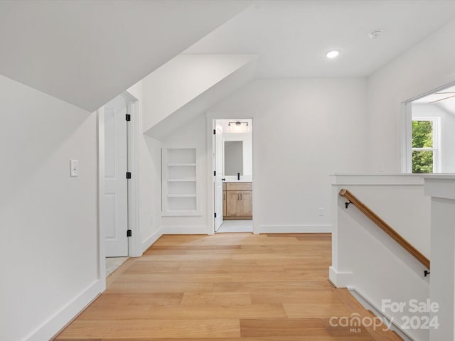 hall featuring built in features and light wood-type flooring