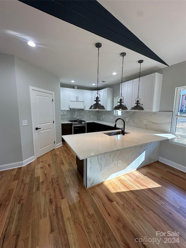 kitchen featuring kitchen peninsula, dark wood-type flooring, sink, white cabinets, and stainless steel stove