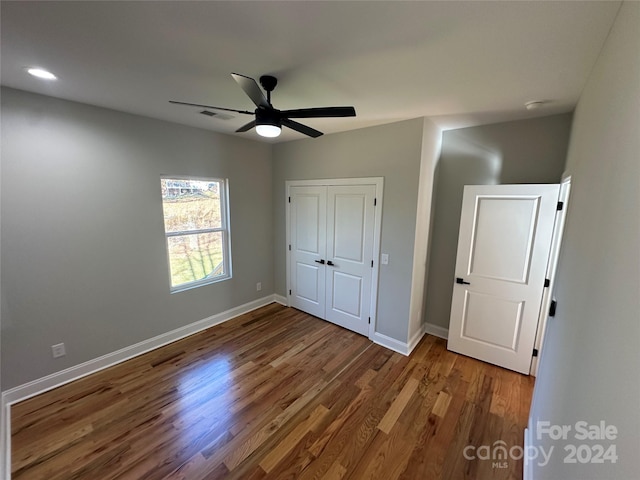 unfurnished bedroom featuring ceiling fan, a closet, and hardwood / wood-style flooring