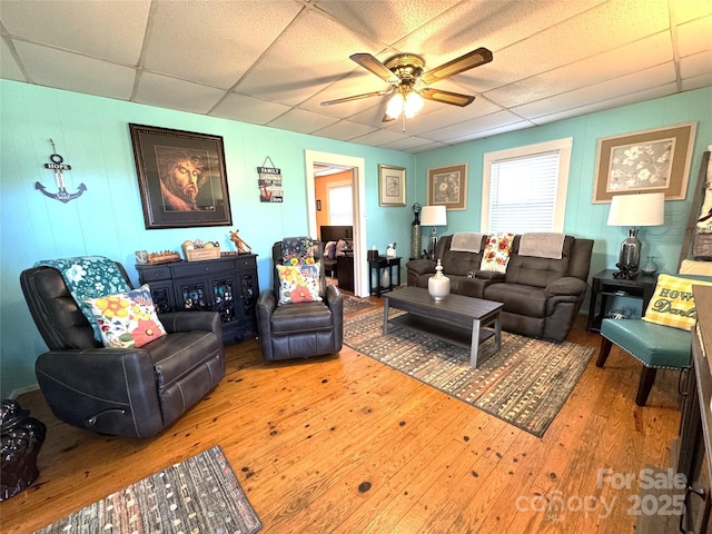 living room featuring wood-type flooring, a paneled ceiling, and ceiling fan