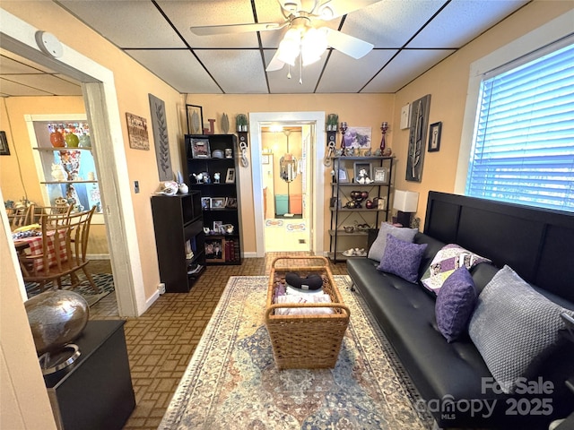 living room with a paneled ceiling and ceiling fan