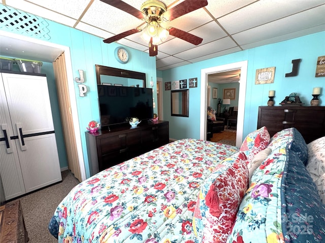 carpeted bedroom featuring a drop ceiling and ceiling fan