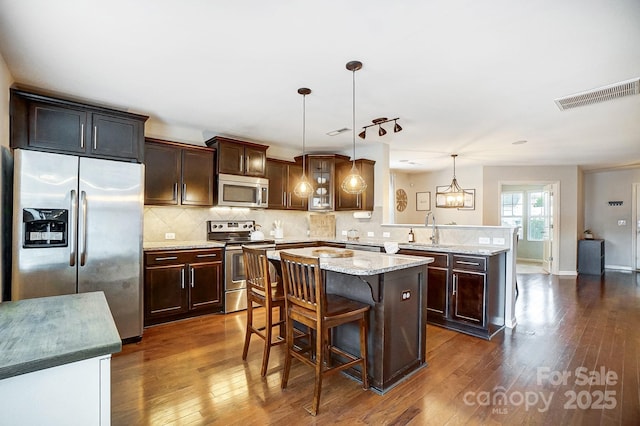 kitchen with sink, kitchen peninsula, decorative light fixtures, a breakfast bar, and appliances with stainless steel finishes