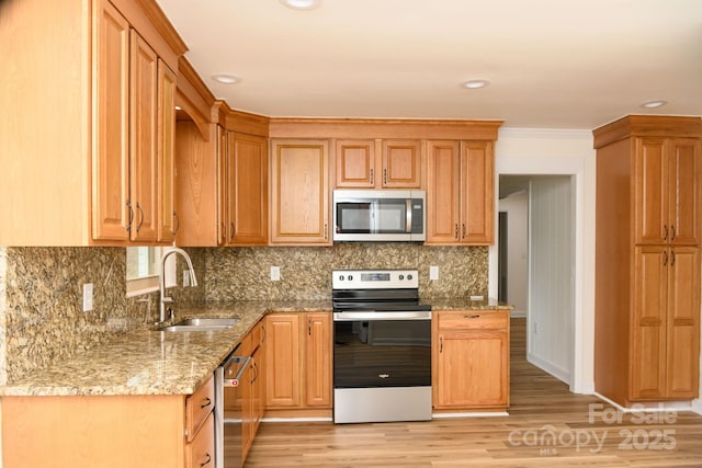 kitchen featuring decorative backsplash, appliances with stainless steel finishes, light wood-type flooring, light stone counters, and sink