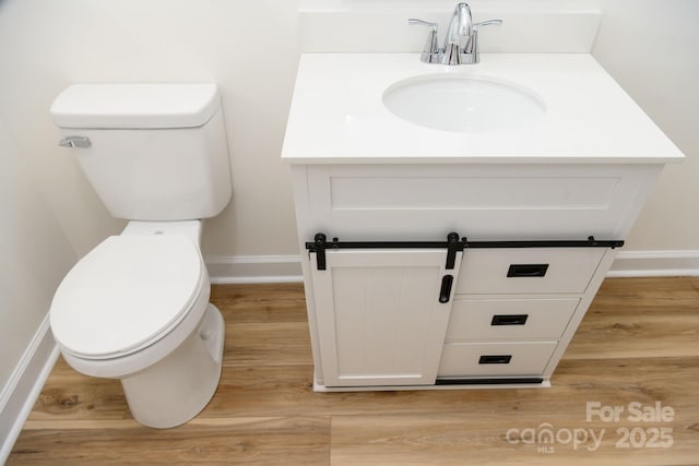 bathroom featuring wood-type flooring, vanity, and toilet