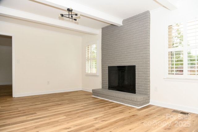 unfurnished living room with beamed ceiling, light wood-type flooring, and a fireplace