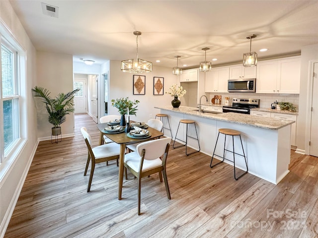 dining room with light hardwood / wood-style floors, sink, and an inviting chandelier