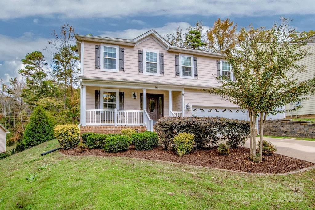 view of front of property with covered porch, a garage, and a front yard