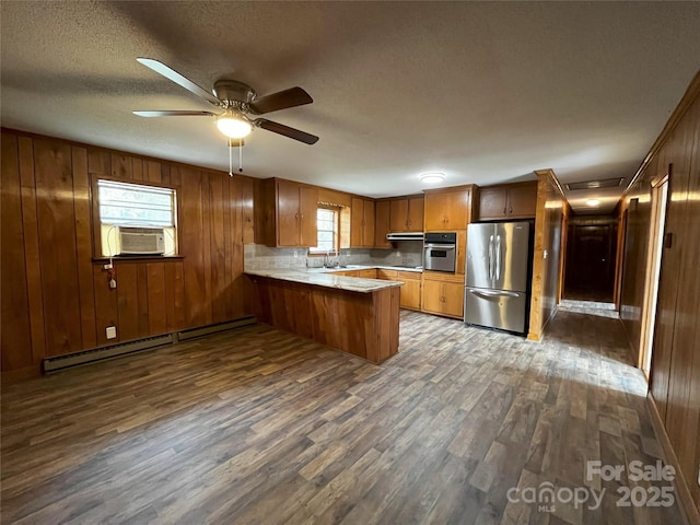 kitchen featuring kitchen peninsula, appliances with stainless steel finishes, dark hardwood / wood-style floors, a baseboard radiator, and sink