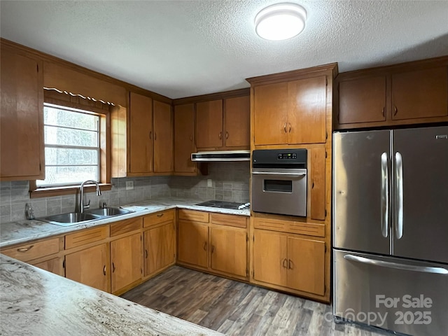 kitchen featuring decorative backsplash, sink, stainless steel appliances, a textured ceiling, and ventilation hood