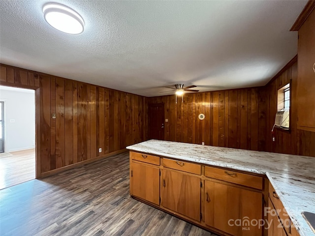 kitchen with a textured ceiling, ceiling fan, dark hardwood / wood-style flooring, and wooden walls