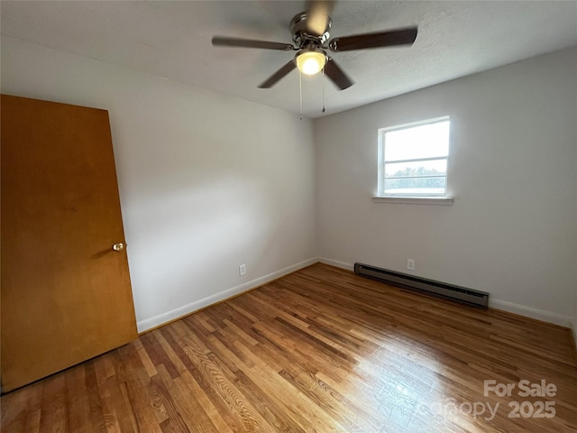 empty room featuring hardwood / wood-style flooring, a baseboard heating unit, and ceiling fan