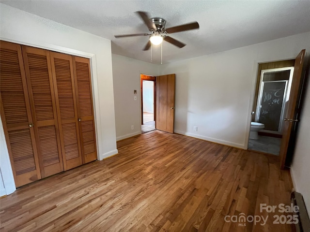 unfurnished bedroom with ceiling fan, ensuite bath, light wood-type flooring, a closet, and a textured ceiling