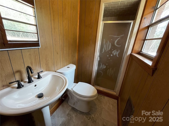 bathroom featuring sink, a wealth of natural light, walk in shower, and wood walls