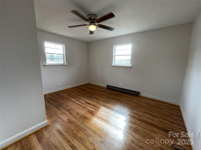 spare room featuring ceiling fan, a baseboard radiator, and wood-type flooring