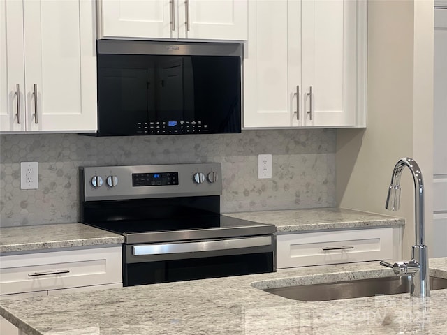 kitchen featuring sink, white cabinets, backsplash, stainless steel range with electric stovetop, and light stone counters