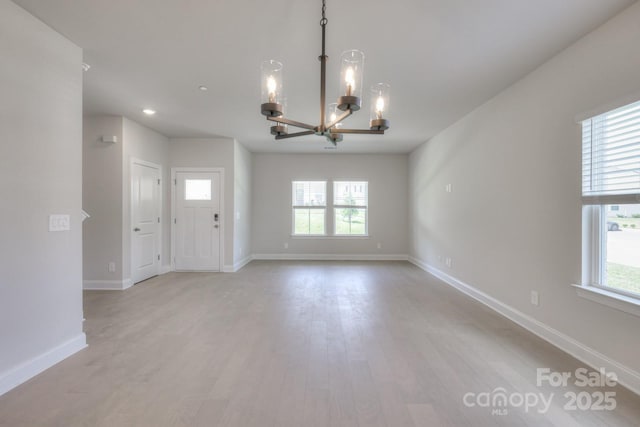 interior space with an inviting chandelier, a healthy amount of sunlight, and light wood-type flooring