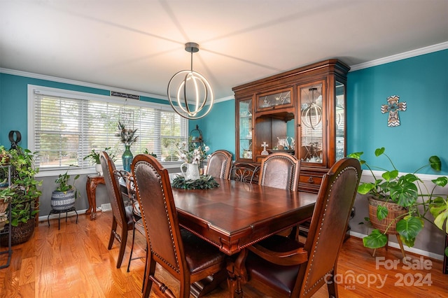 dining space with ornamental molding, light hardwood / wood-style floors, and an inviting chandelier