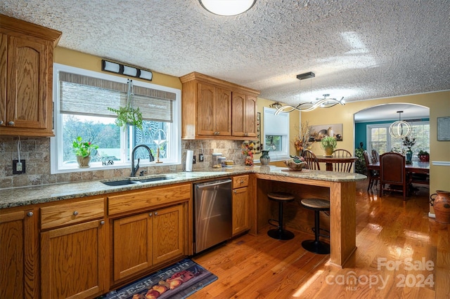 kitchen with dishwasher, hanging light fixtures, sink, and wood-type flooring