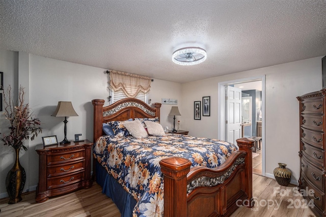 bedroom with ensuite bathroom, light hardwood / wood-style floors, and a textured ceiling