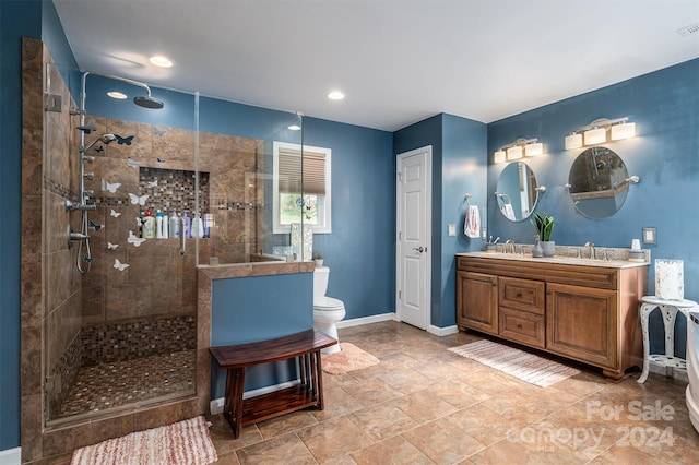 bathroom featuring vanity, toilet, and a tile shower