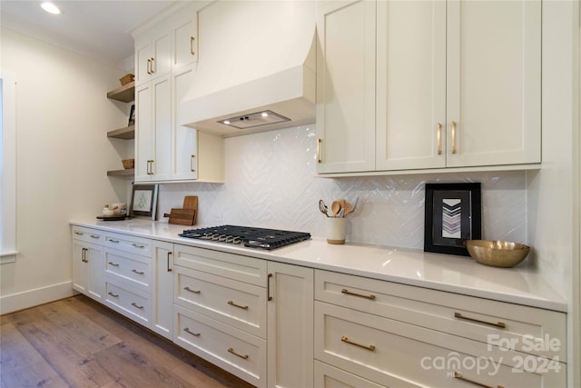 kitchen featuring decorative backsplash, hardwood / wood-style flooring, stainless steel gas cooktop, and custom exhaust hood