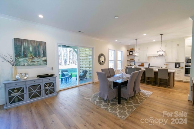 dining area featuring light wood-type flooring and ornamental molding