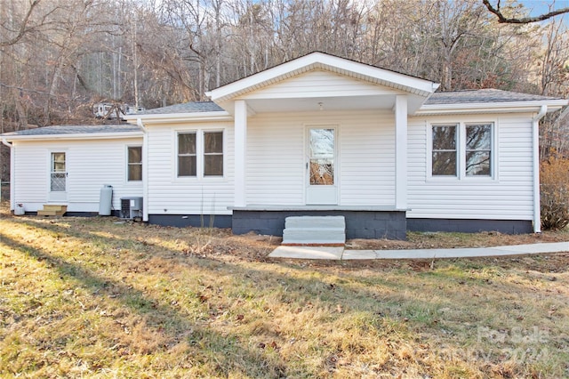 view of front of house with cooling unit and a front lawn