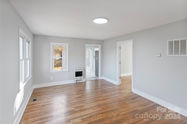 unfurnished living room with hardwood / wood-style flooring and heating unit