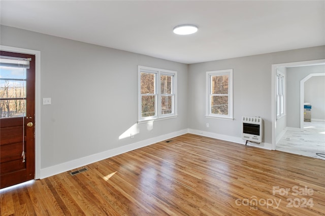 unfurnished living room with plenty of natural light, light hardwood / wood-style floors, and heating unit