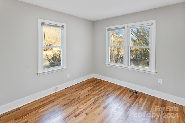 unfurnished room featuring a wealth of natural light and hardwood / wood-style floors