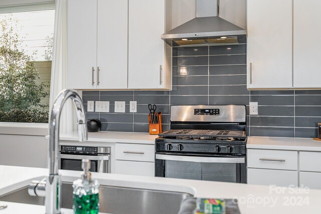 kitchen featuring white cabinets, appliances with stainless steel finishes, and wall chimney range hood