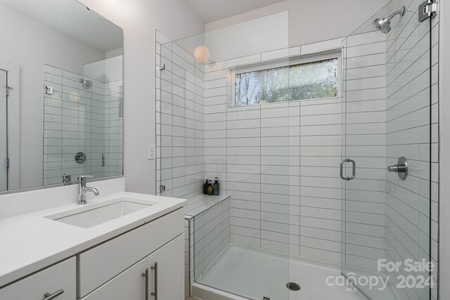 bathroom featuring a shower with shower door and vanity