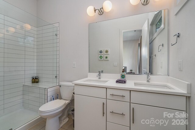 bathroom with vanity, tile patterned flooring, toilet, and tiled shower