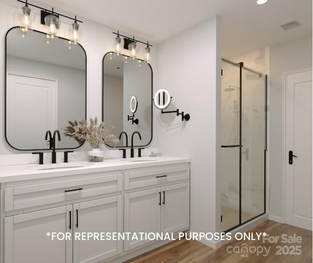 full bath featuring visible vents, a sink, a marble finish shower, and wood finished floors