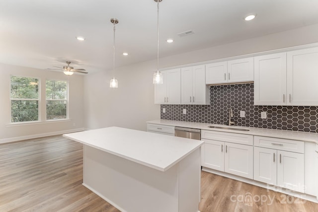 kitchen with white cabinetry, pendant lighting, light countertops, and a sink