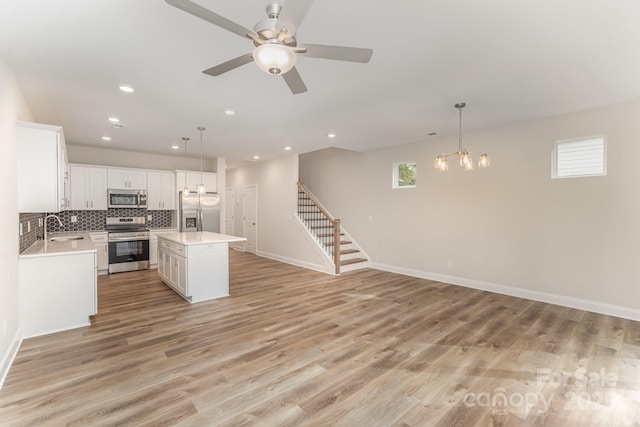 kitchen featuring a sink, light countertops, appliances with stainless steel finishes, a center island, and pendant lighting