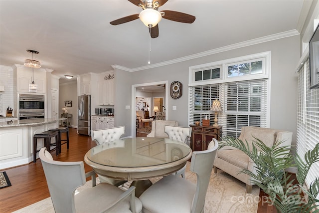 dining room with ceiling fan, dark wood-type flooring, and ornamental molding