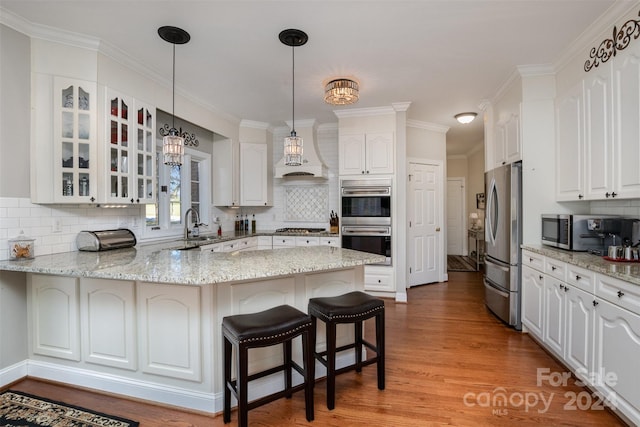 kitchen featuring white cabinets, light hardwood / wood-style floors, kitchen peninsula, and appliances with stainless steel finishes