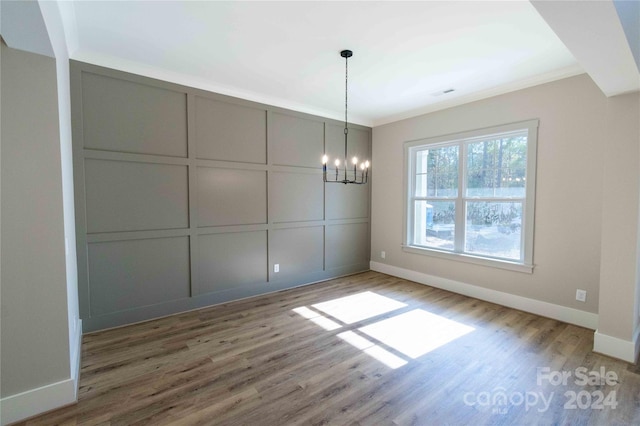 unfurnished dining area featuring hardwood / wood-style flooring and an inviting chandelier