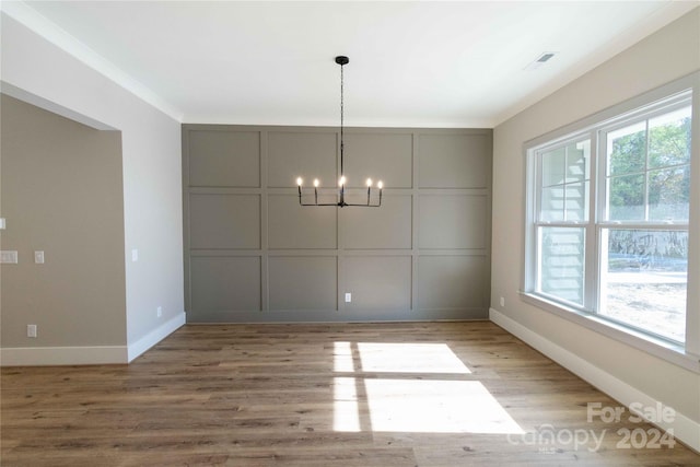 unfurnished dining area featuring a notable chandelier, a healthy amount of sunlight, and light hardwood / wood-style floors