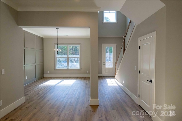 foyer with a notable chandelier, wood-type flooring, and crown molding