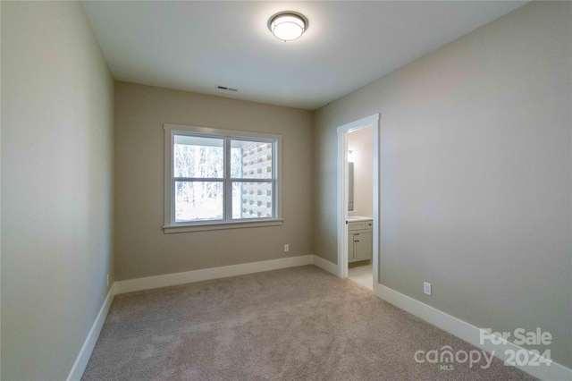 unfurnished bedroom featuring ensuite bath and light carpet